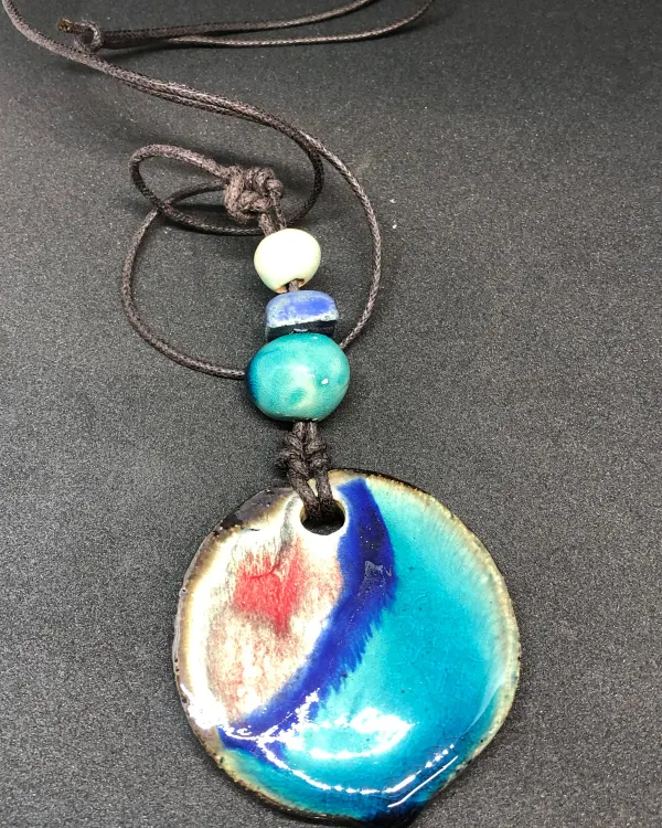 Collana Acquerello — Un disco color crema con pennellate blu, su cordino con perline in ceramica.
