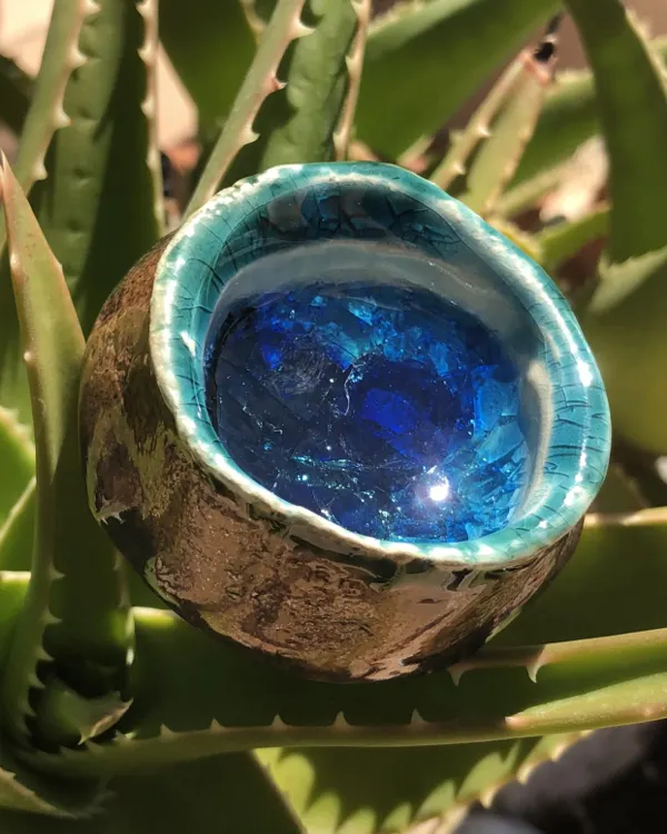 Ciondolo Coppa Blu — Una piccola coppa con l'esterno metallico e un lago di vetro blu.