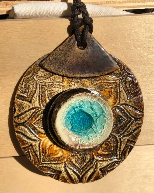 Collana Mandala — Un mandala in rilievo color bronzo con un cuore di vetro turchese.