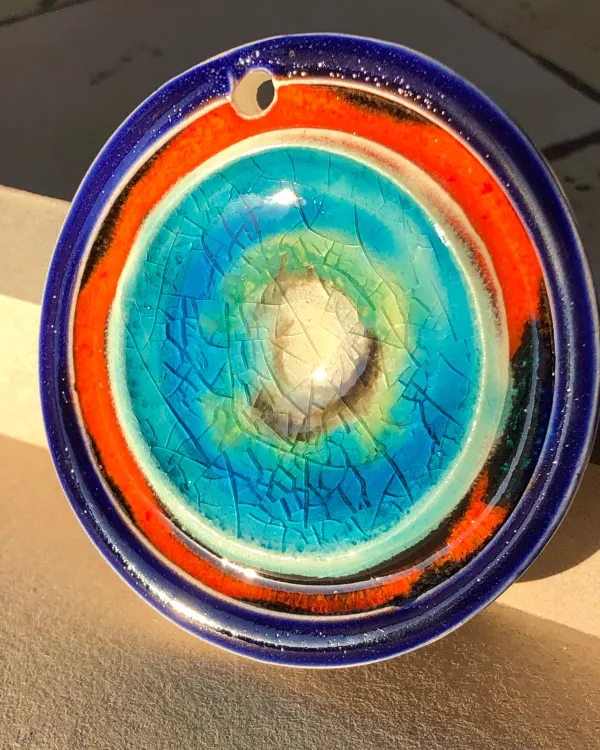 Ciondolo Tramonto — Bordo blu cobalto, un anello arancione e un centro turchese craquelé.